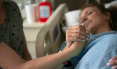 Woman holding hand in hospital bed
